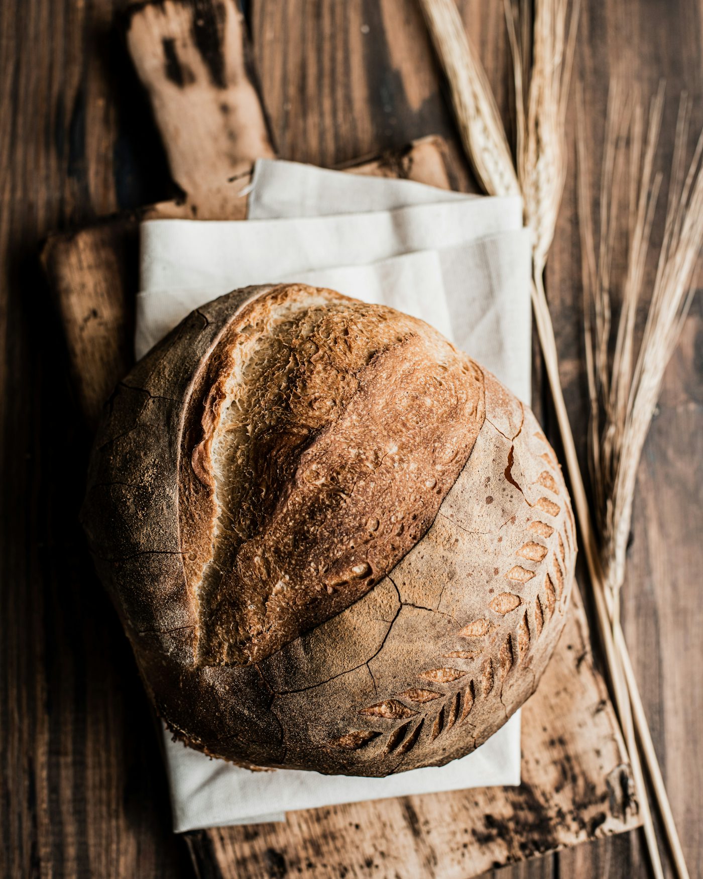 A round sourdough loaf with a dark, floured crust on a wooden board
