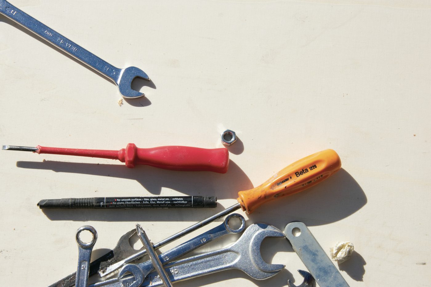 Spanners, screwdrivers and a marker pen laid out on a pale board